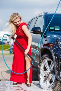 woman cleaning car with pressure washer